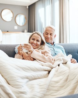 Paar kuschelt unter einer Decke auf dem Sofa